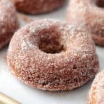 Apple cider donuts on baking sheet with parchment paper.