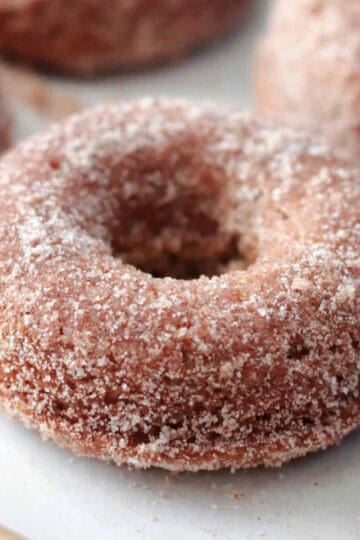 Apple cider donuts on baking sheet with parchment paper.