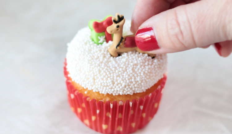 hand placing candy reindeer on cupcake