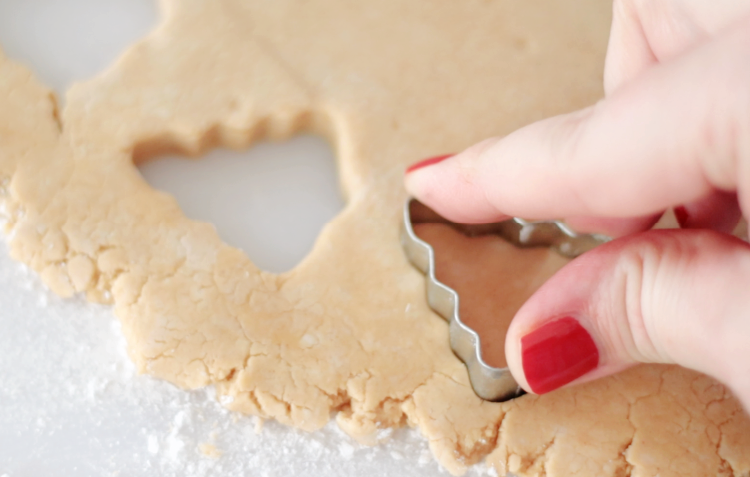 hand pressing tree cookie cutter into peanut butter dough