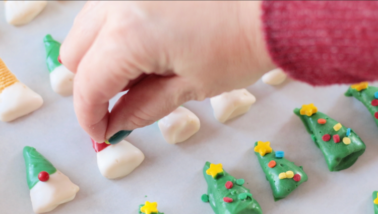 hand adding candy noses to gnomes