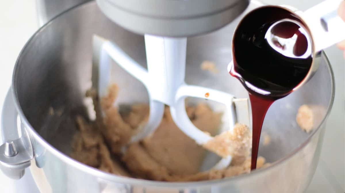 Measuring cup of molasses pouring into bowl.