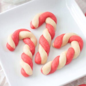 3 candy cane cookies on a white plate.