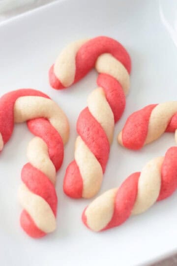 3 candy cane cookies on a white plate.