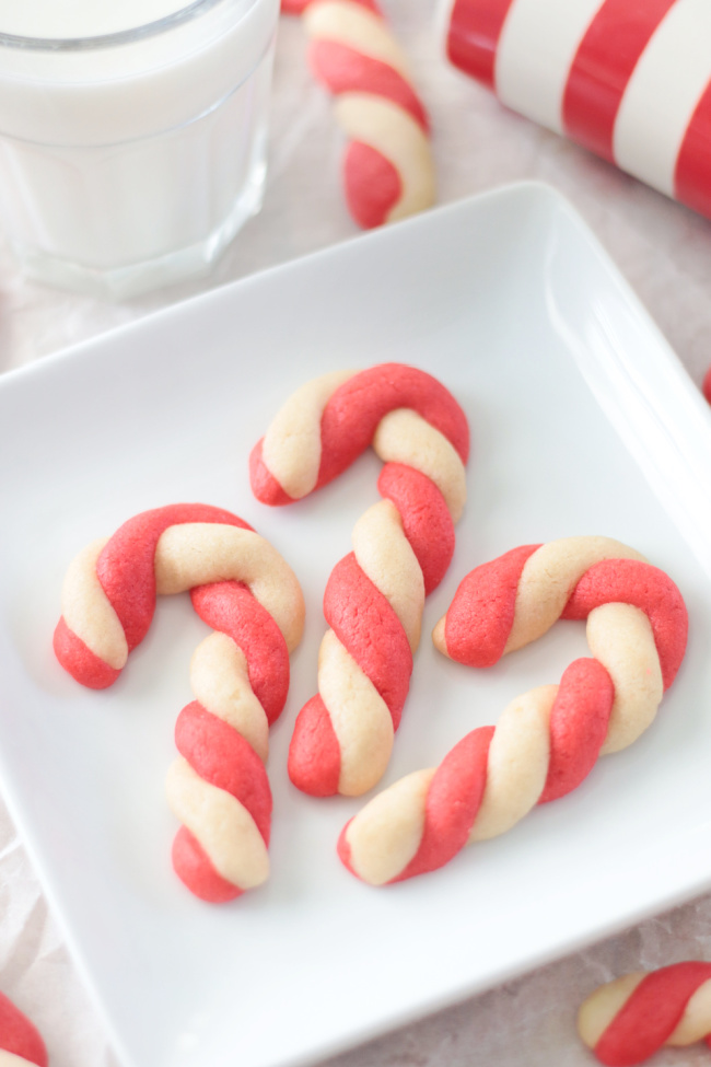 3 candy cane cookies on a white plate.
