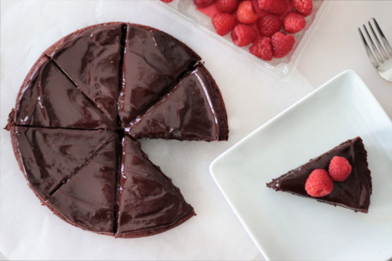 sliced flourless chocolate cake and container of fresh raspberries