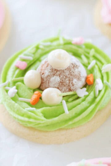 Oval bunny butt sugar cookie with green frosting and donut hole on top.