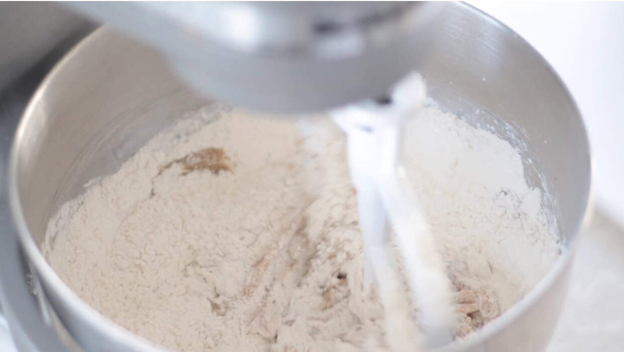Flour and dry ingredients in bowl of a stand mixer.