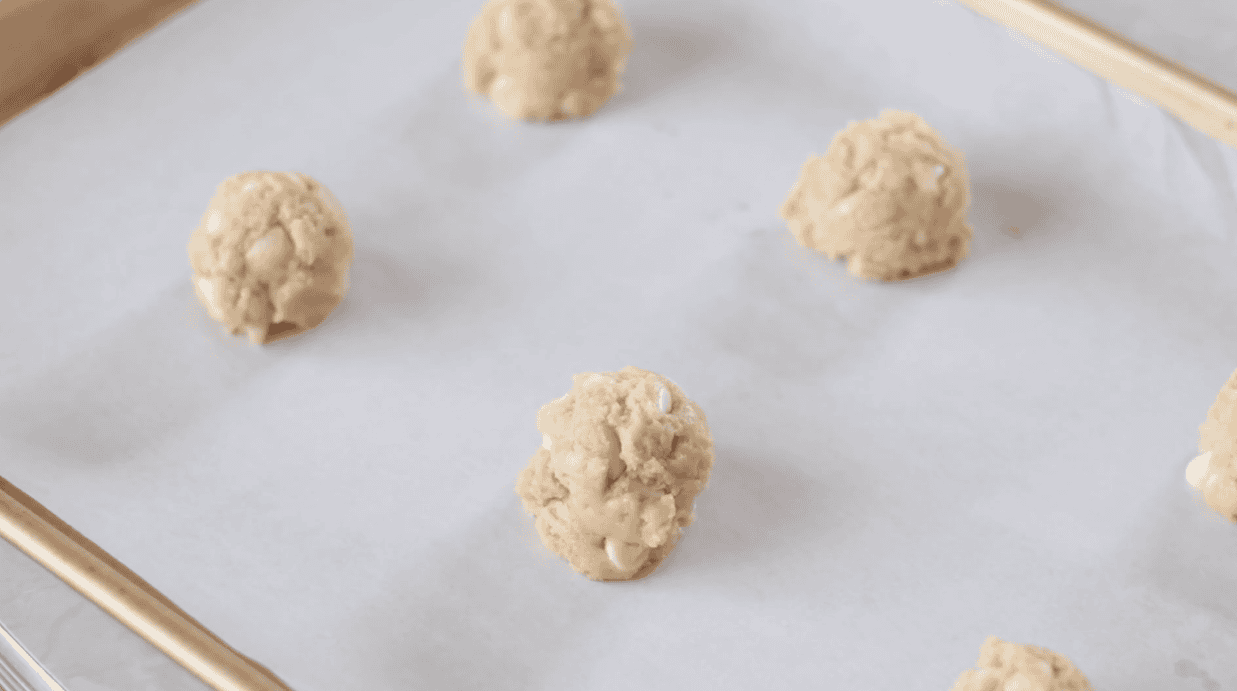 Cookie dough balls on a baking sheet lined with parchment paper.
