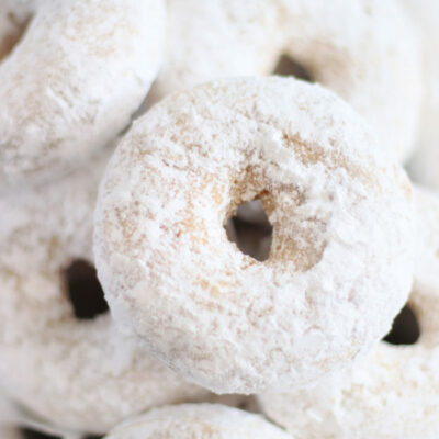 powdered sugar donuts stacked in a pile