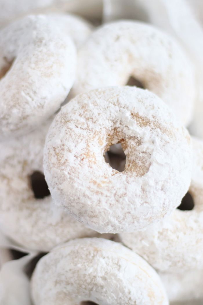 powdered sugar donuts stacked in a pile