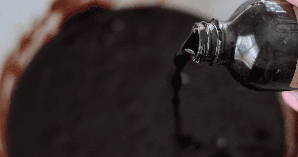 Bottle of vanilla extract pouring some into batter.