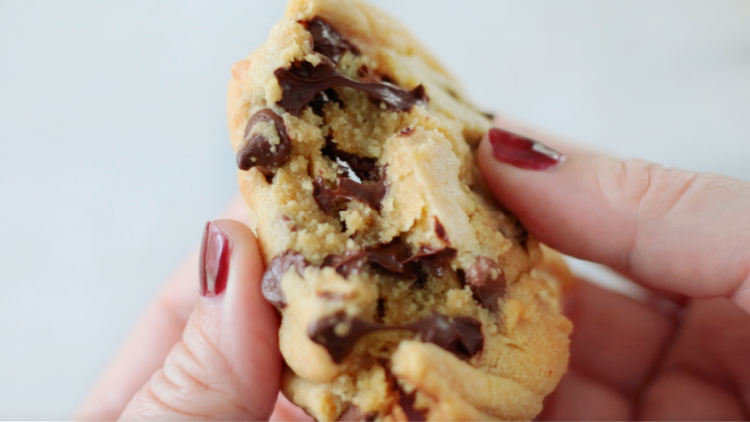 hand breaking chocolate chip cookie in half