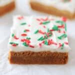 Frosted gingerbread cookie bars cut into squares on parchment paper.