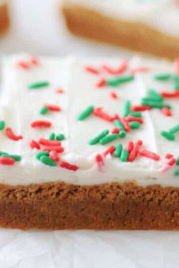 Frosted gingerbread cookie bars cut into squares on parchment paper.