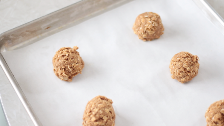 cookie dough balls on parchment paper lined baking sheet