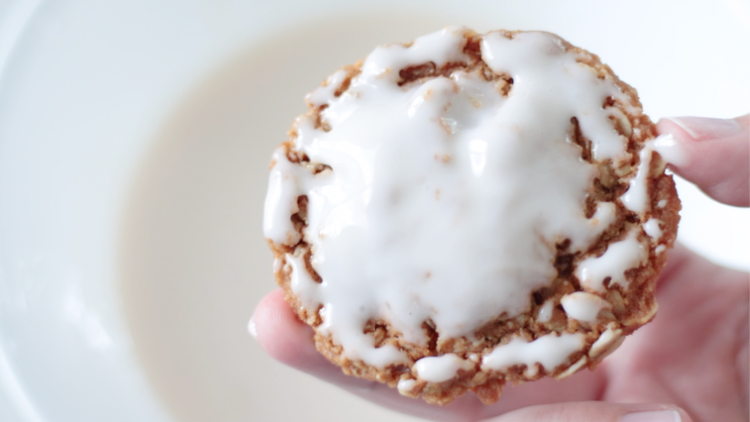 hand holding freshly iced oatmeal cookie