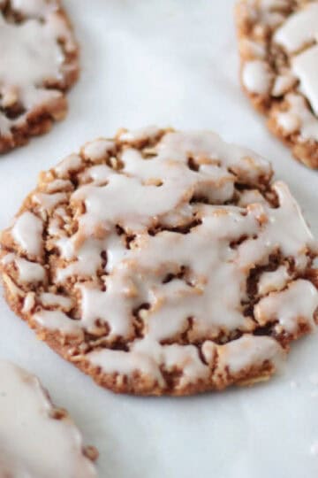 Iced ginger oatmeal cookies on parchment paper.