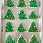Frosted green tree sugar cookies on baking sheet.