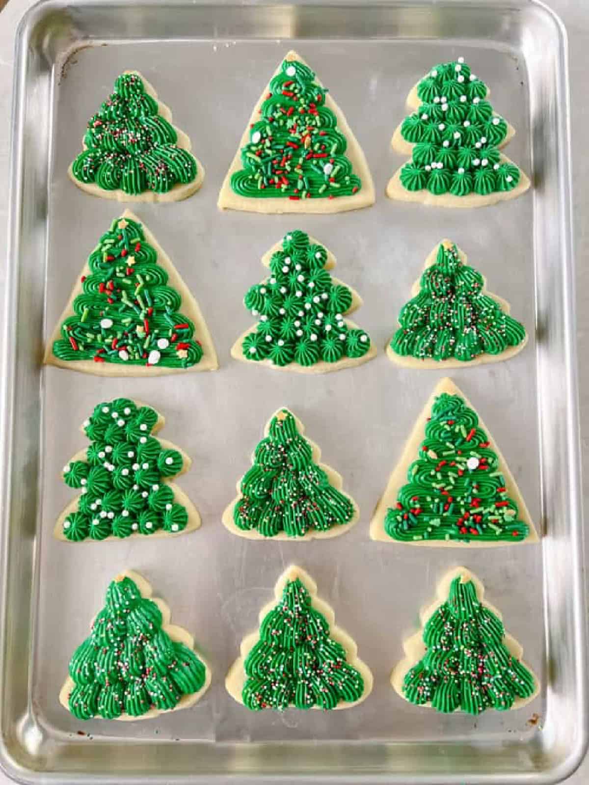 Frosted green tree sugar cookies on baking sheet.