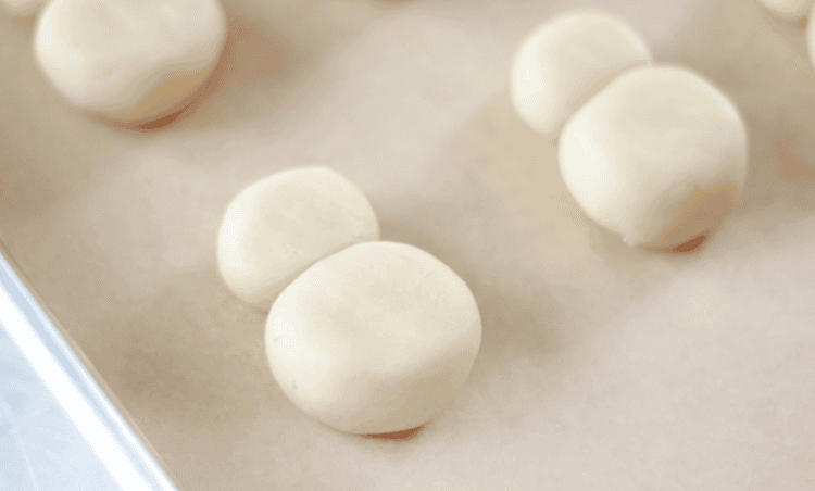 Cookie dough balls pressed down to create snowman shape.