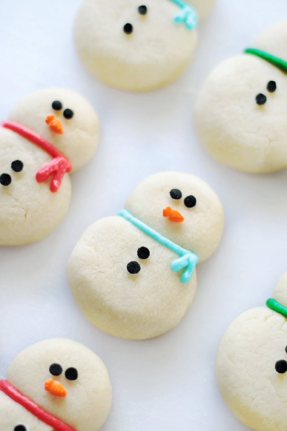 Snowman cookies decorated with frosting and candy eyes.