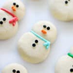 Snowman cookies decorated with frosting and candy eyes.