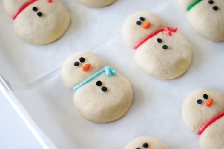 Baking sheet of decorated snowman cookies.