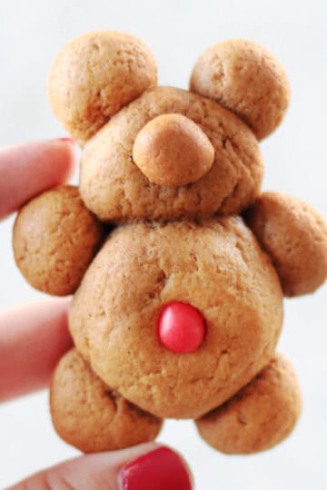 Hand holding a teddy bear gingerbread cookie.