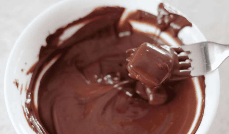bowl of melted chocolate and fork dipping cheez it bites into chocolate