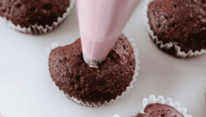 piping bag filling cupcake with frosting