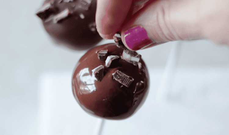 hand sprinkling chopped andes mints onto cake pop