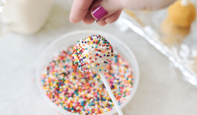cake pop with sprinkles being added to it