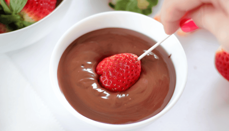 strawberry being dipped into melting chocolate