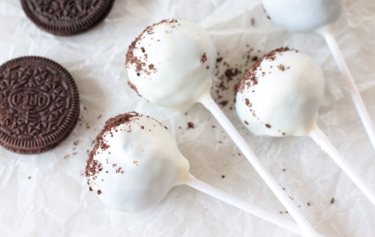 4 cake pops and oreo cookies on parchment paper