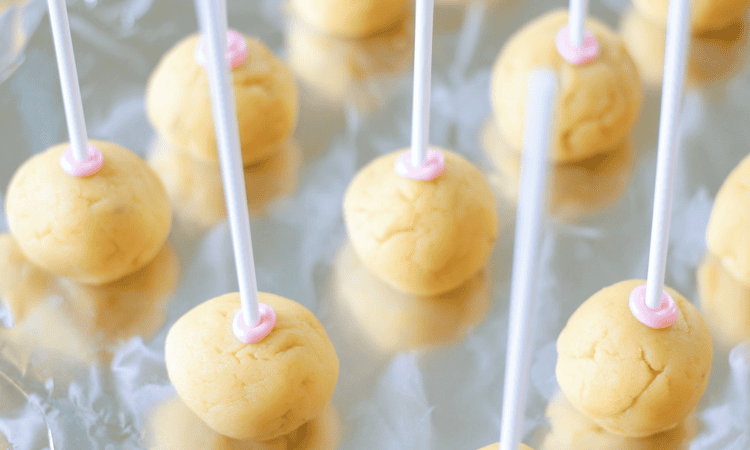 unfrosted cake pop balls on baking sheet with lollipop sticks