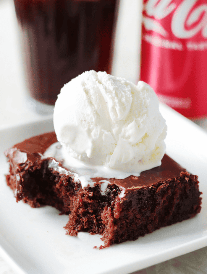 slice of coca cola cake with scoop of vanilla ice cream on plate