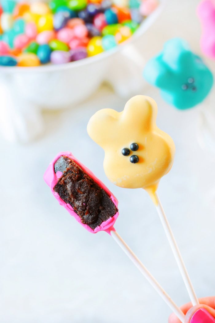 one brownie bunny pop with bite taken out of it and one yellow bunny pop