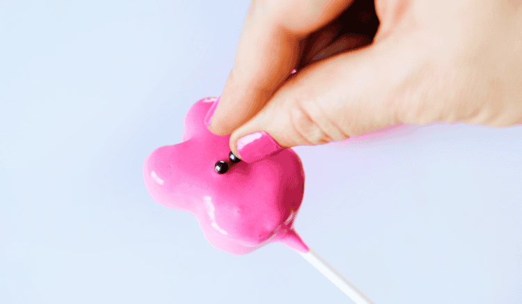 hand adding candy eyes to bunny pops