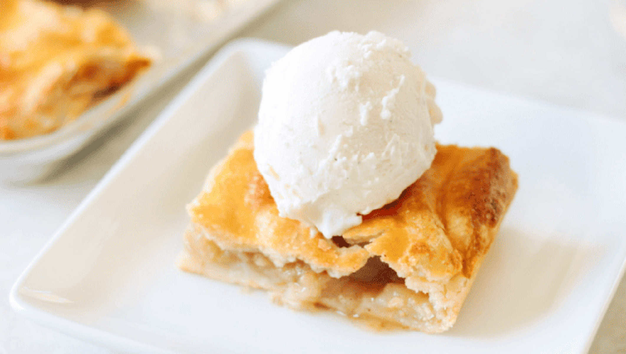 White plate with slice of apple slab pie and scoop of vanilla ice cream.