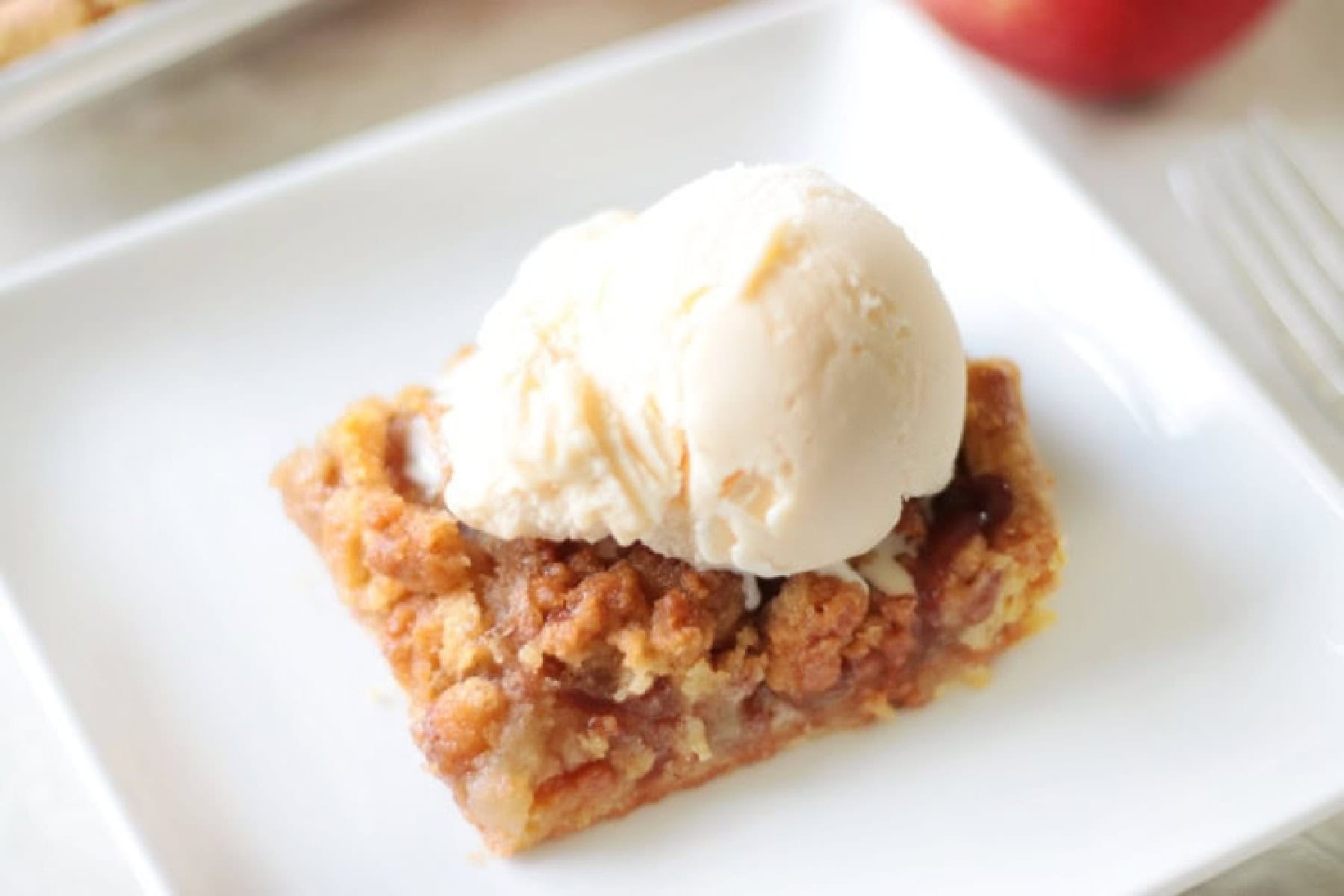 White plate with slice of pie and scoop of vanilla ice cream on top.