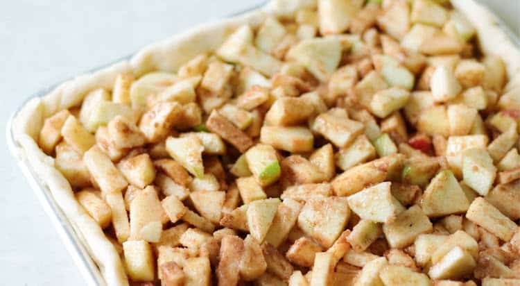 Crust rolled out in sheet pan and apple pie filling spread on top.