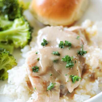pork chops served over rice with a roll and steamed broccoli.