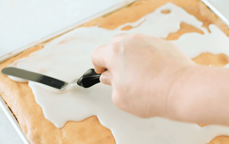 hand spreading icing over