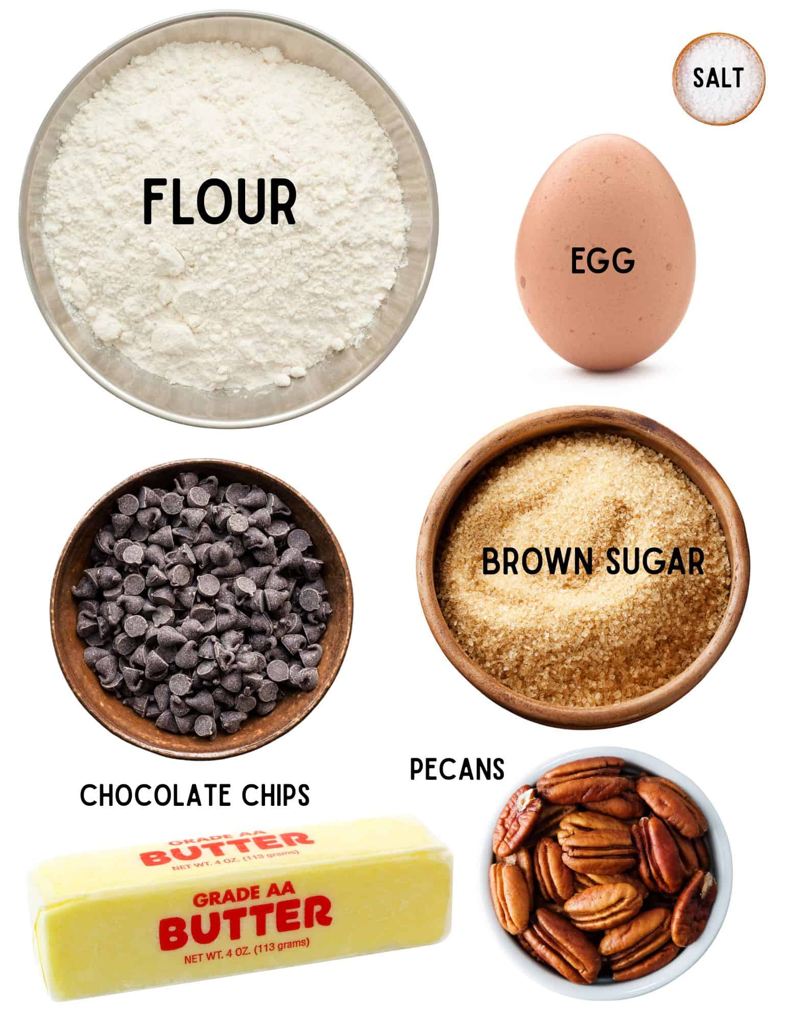 Bowls of flour, salt, brown sugar, pecans, chocolate chips, egg and stick of butter.