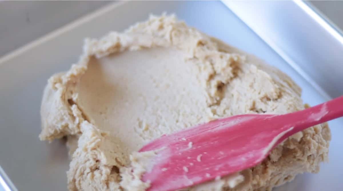 Toffee bar cookie dough spread into baking pan.