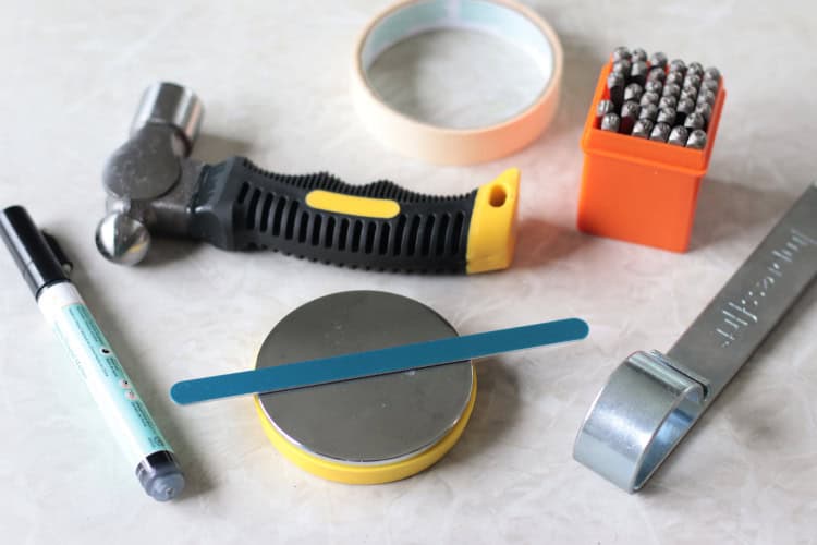 enamel pen, stamping block, bracelet blank, bending tool, hammer, tape and metal stamps