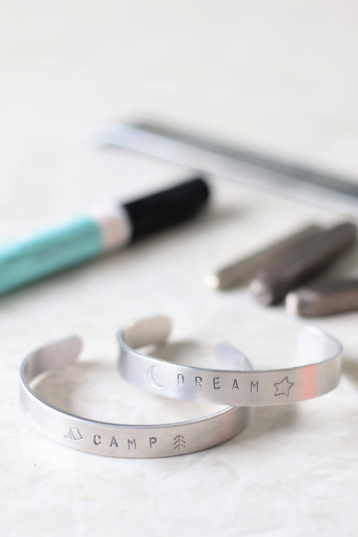 two stamped bracelets and pile of metal stamps