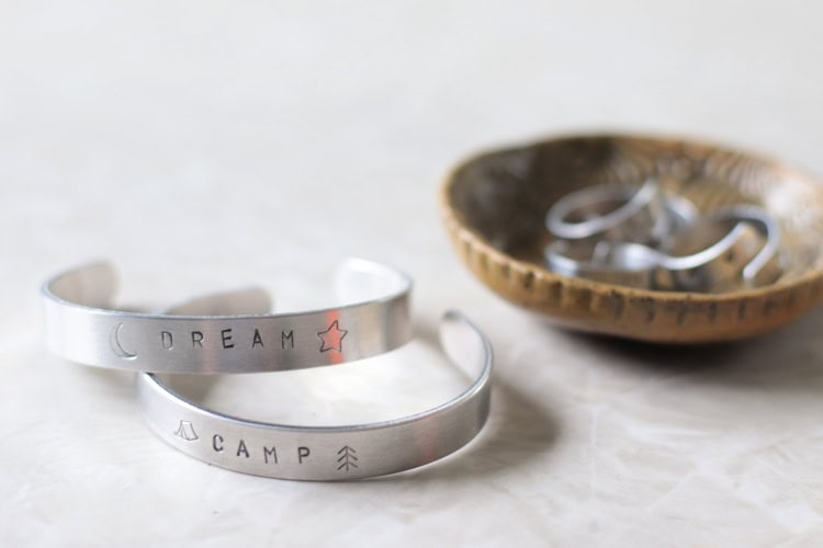 two aluminum stamped bracelets on table