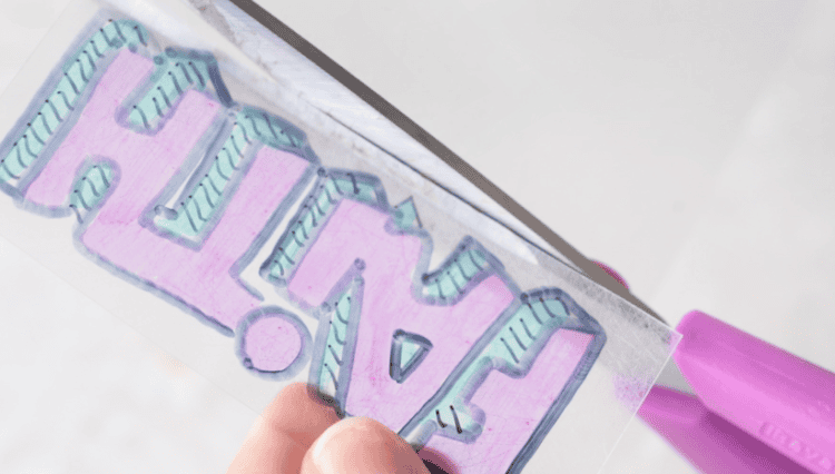 scissors cutting around edge of YW camp shrinky dink